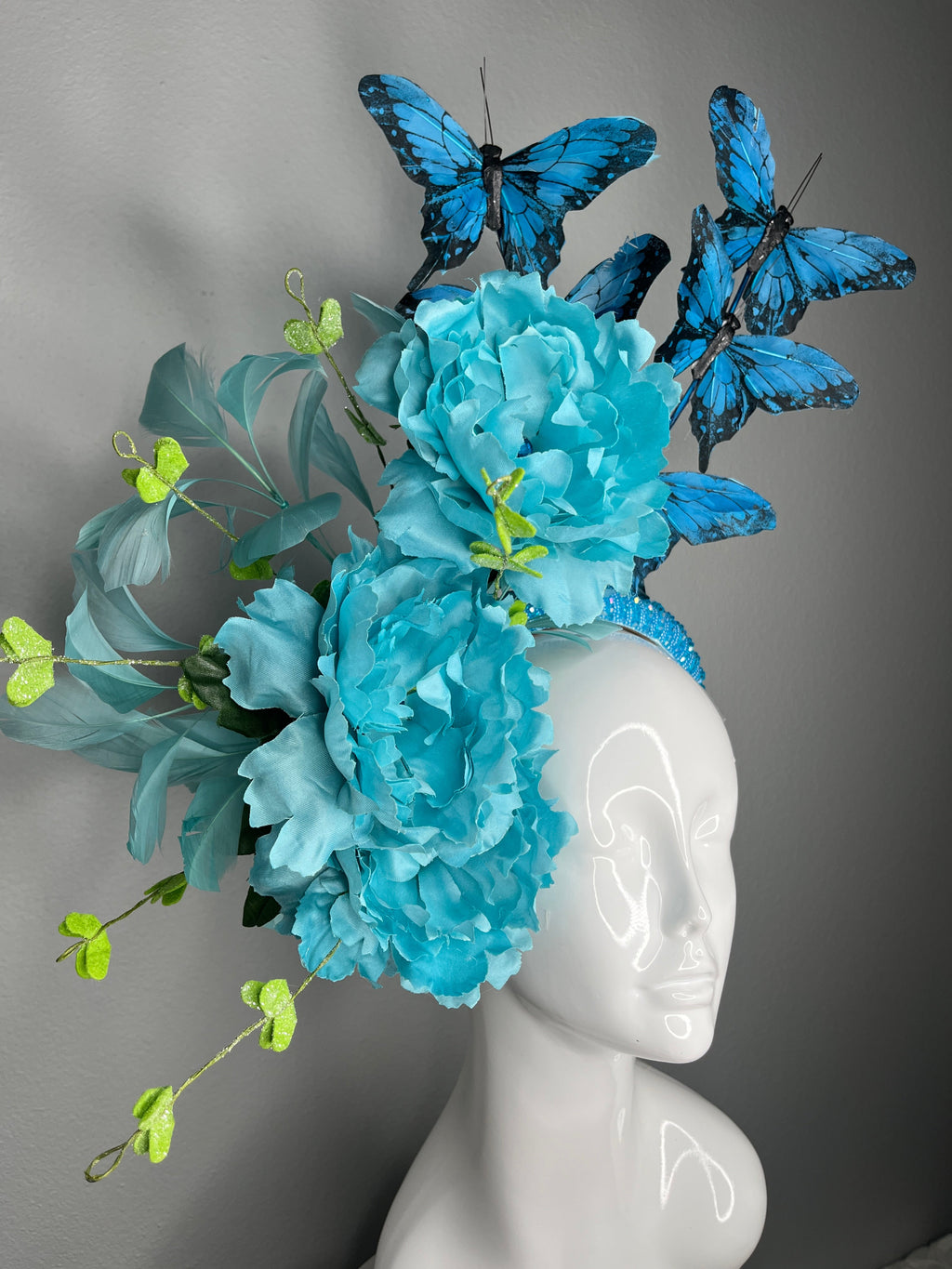 Türkisfarbene Blumen Schmetterling Fascinator-Haarreif Statement Derby-Hut mit blauen Schmetterlingen übergroße Blüten